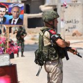 (FILES) In this file photograph taken on August 20, 2018, members of Russian and Syrian forces stand guard near posters of Syrian President Bashar al-Assad and his Russian counterpart Vladimir Putin at the Abu Duhur crossing on the eastern edge of Idlib province. - Russia and Turkey are in intense negotiations to ensure the rebel-held province of Idlib does not become a breaking point in their alliance on Syria, but the long term fate of the area still risks provoking a rupture, analysts say. President Vladimir Putin and Turkish counterpart Recep Tayyip Erdogan have spearheaded an unlikely but so far sustained partnership to bring peace to Syria since late 2016, despite being in theory on opposite sides of the civil war.The cooperation now faces its biggest test over Syria's northwestern province of Idlib, bordering Turkey, which Syrian President Bashar al-Assad wants to recapture to complete a string of military successes. (Photo by George OURFALIAN / AFP)GEORGE OURFALIAN/AFP/Getty Images